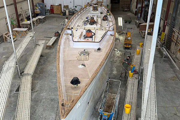 the base of a sailboat being build in a warehouse, with various equipment being used on it
