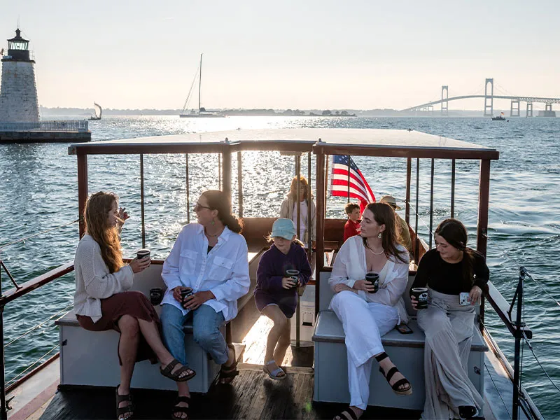 a group of woman all sitting on benches, chatting with each other, aboard a motor yacht from classic harbor line